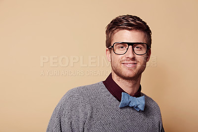 Buy stock photo Portrait, glasses and bowtie for fashion with a man on space in studio for vision or trendy style. Face, smile and eyewear with a confident young model on a tan background in a casual clothing outfit