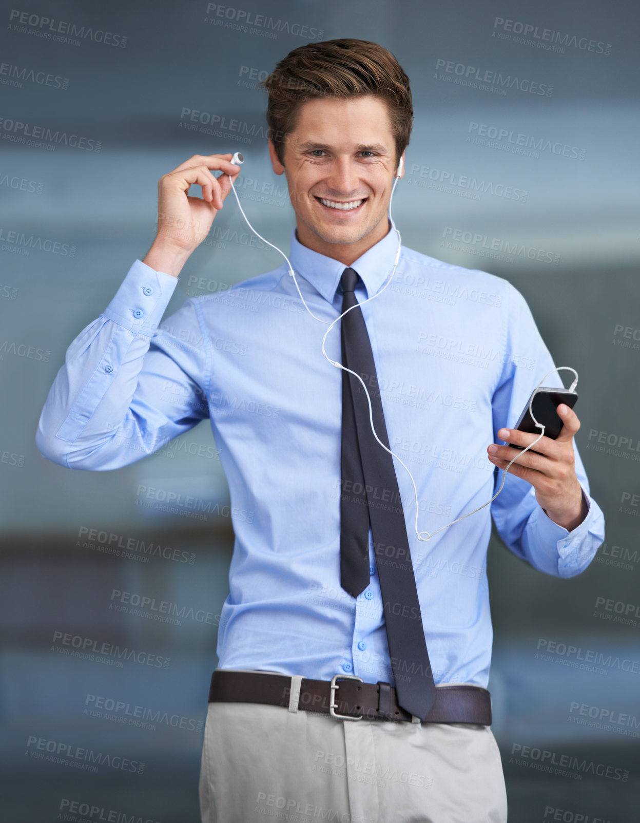 Buy stock photo Portrait of a handsome young businessman using his smartphone as an mp3 player