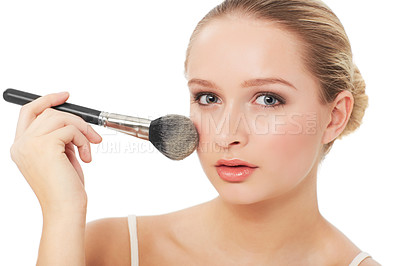Buy stock photo A beautiful young woman applying blush to her cheeks while isolated on a white background