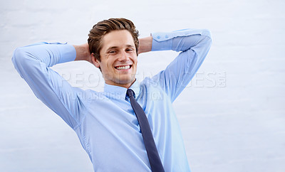 Buy stock photo A satisfied young businessman leaning back with his hands behind his head