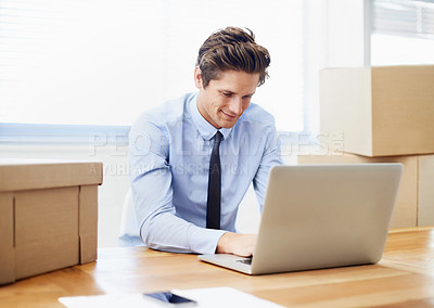 Buy stock photo A young businessman working on his laptop after moving offices