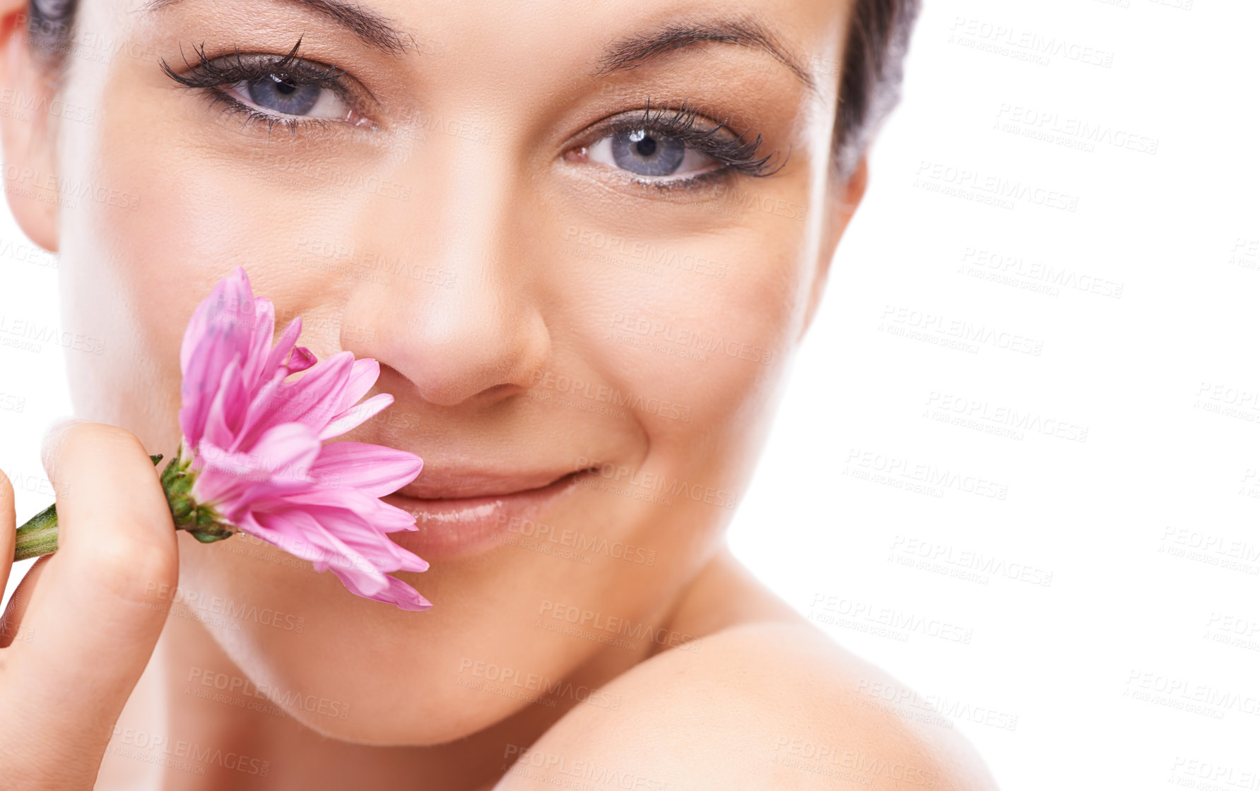 Buy stock photo A lovely young woman smiling at the camera while sniffing a pink flower