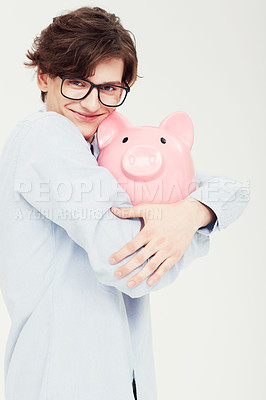 Buy stock photo Portrait of a young man hugging a piggy bank closely to himself