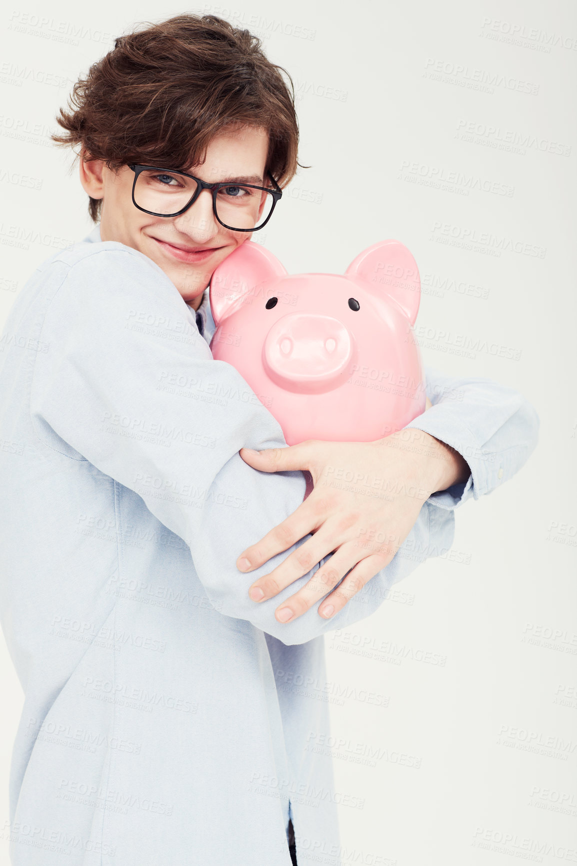 Buy stock photo Portrait of a young man hugging a piggy bank closely to himself