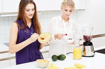Buy stock photo Two friends making health shakes together in the kitchen