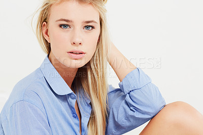 Buy stock photo A gorgeous young blonde woman in a blue shirt looking at the camera with her hand in her hair - portrait