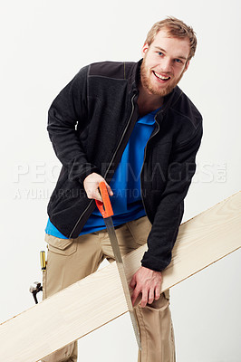 Buy stock photo Portrait of a young carpenter sawing a piece of wood against his leg