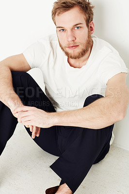 Buy stock photo Portrait of a young man sitting on the floor against a wall
