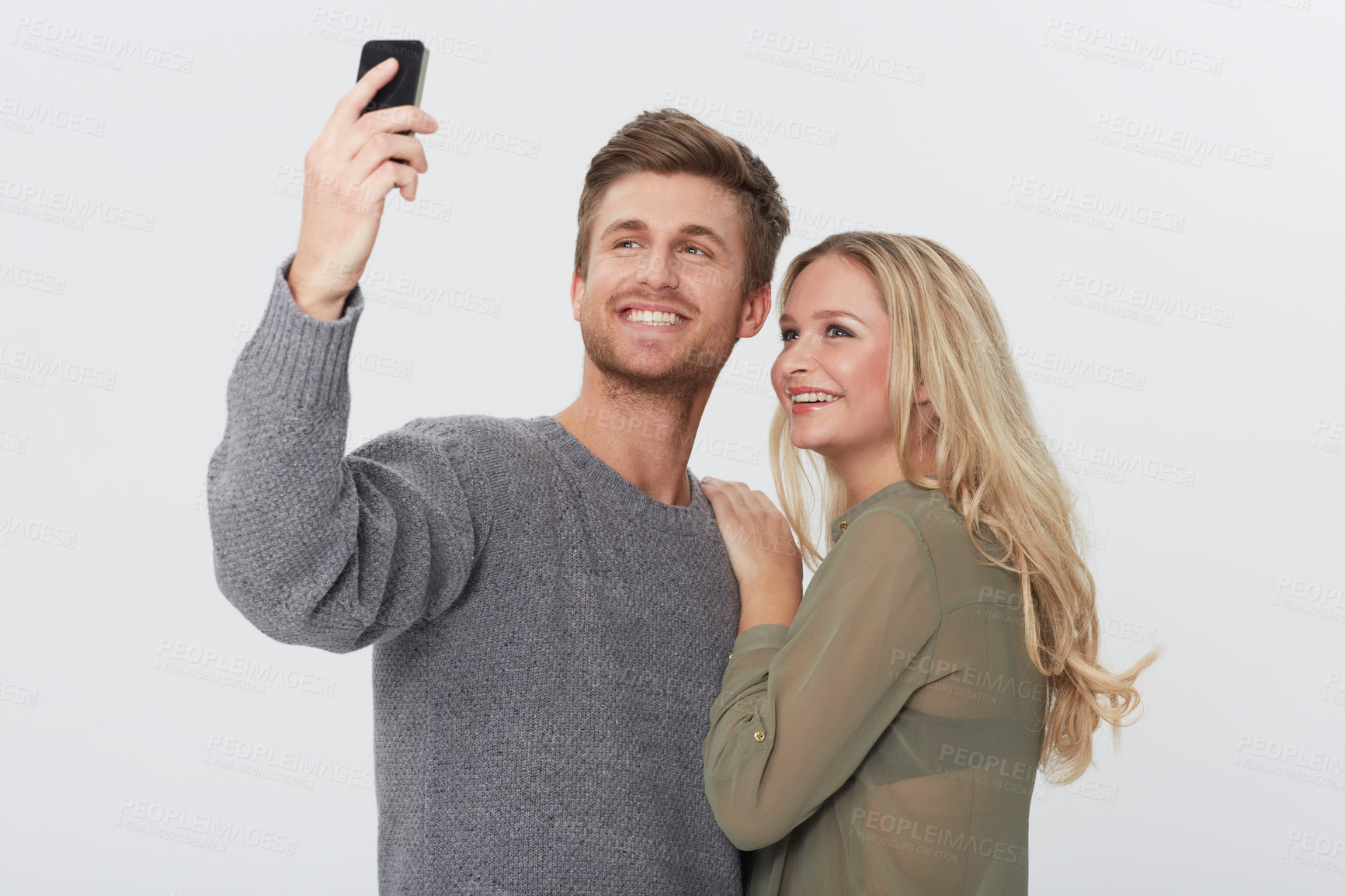 Buy stock photo Studio portrait of a happy young couple taking a self portrait with a camera phone