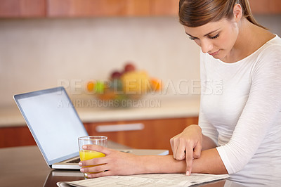 Buy stock photo Woman, reading newspaper and kitchen with laptop, drinking orange juice and remote work at home. Computer, print media or freelancer check newsletter report for research, article information or story