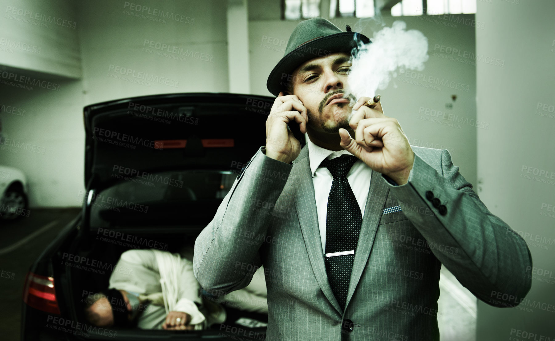 Buy stock photo Phone call, car and mafia with hostage in trunk for negotiation, kidnapping danger and crime. Smoking, gangster criminal and business person in boot for abduction, terrorism and money in parking lot