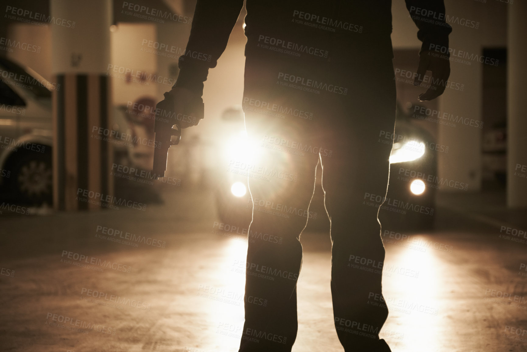 Buy stock photo A criminal holding a revolver about to hijack someone in an underground parking lot