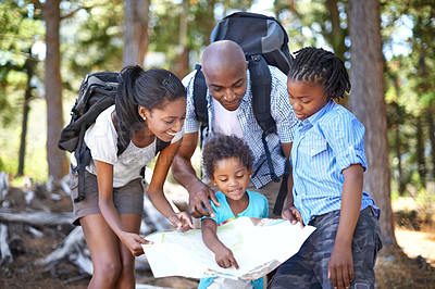Buy stock photo A happy african family looking at a map while taking a hike together