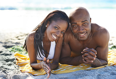 Buy stock photo Black couple with towel, beach and relax in sunshine on holiday with travel, sand and mountain. Sun tan, ocean vacation and people in swimwear on island adventure with blue sky, summer and sea water.