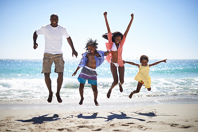 Buy stock photo An excited african american family jumping into the air on the beach with a beautiful ocean in the background