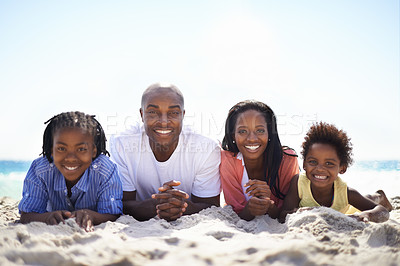 Buy stock photo An african-american family lying in a line on the beach