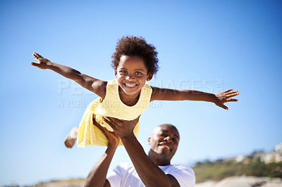 Buy stock photo A father lifting his adorable daughter into the air while enjoying a day at the beach