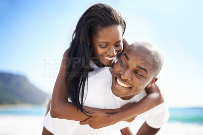 Buy stock photo A handsome african-american man giving his girlfriend a piggyback on the beach