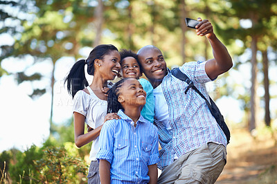 Buy stock photo Shot of a happy-looking family taking a self portrait with a camera phone while out  hiking in the forest