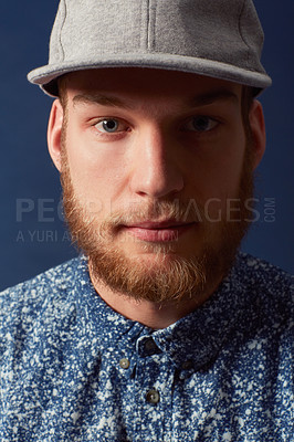 Buy stock photo Man, fashion and face with hat in a studio, denim and trendy isolated on blue background. Irish model with hipster beard, ginger and serious in portrait, stylish and fashionable shirt in headshot