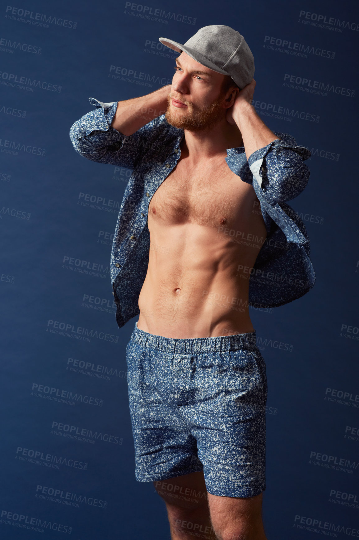 Buy stock photo Fashion, body or model with six pack in studio on a blue background in an open unbuttoned shirt. Thinking, chest or handsome male person posing on color wall for masculine style with a trendy cap