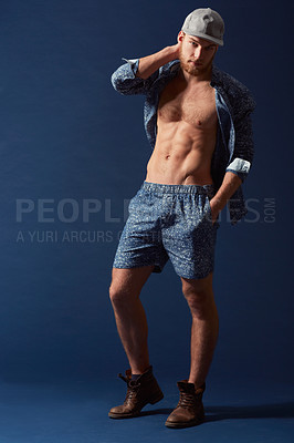 Buy stock photo Fashion, portrait or model with six pack in studio on a blue background in an open unbuttoned shirt. Body, chest or handsome male person posing on color wall for masculine style with a trendy cap