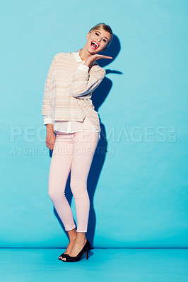 Buy stock photo A lovely young woman in fashionable retro attire smiling with her palm held open beneath her face