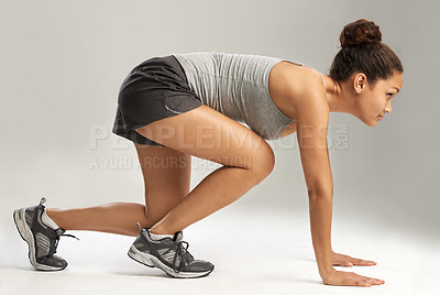 Buy stock photo A young woman in the start position for a race against a grey background