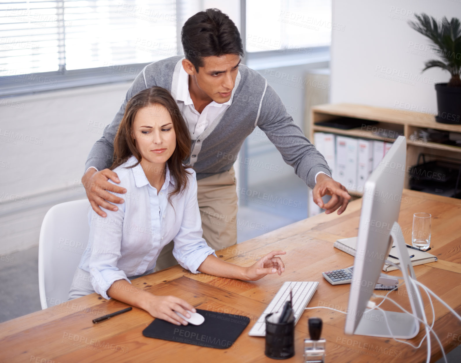 Buy stock photo A young woman looking uncomfortable as her boss puts his hand on her shoulder