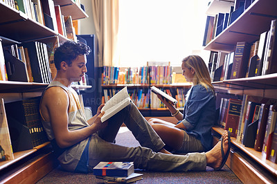 Buy stock photo Two students reading separate textbooks in the library
