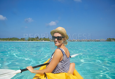 Buy stock photo A beautiful young woman paddling on a boat in a tropical ocean