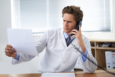 Buy stock photo Document, phone call and man doctor in his office for telehealth consultation at hospital. Confused, professional and young male healthcare worker on mobile discussion with landline in medical clinic