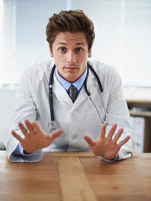 Buy stock photo Shot of a young doctor gesturing 'not to worry' to the camera
