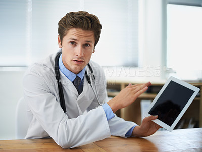 Buy stock photo Shot of a young doctor explaining something while holding a digital tablet