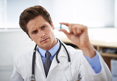 Buy stock photo Curious man, doctor and thinking with pill for healthcare, cure or drugs at hospital or office. Male person, surgeon or medical nurse looking at medication in research, study or examination at clinic