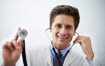 Buy stock photo Shot of a positive-looking doctor holding up the end of a stethoscope toward the camera