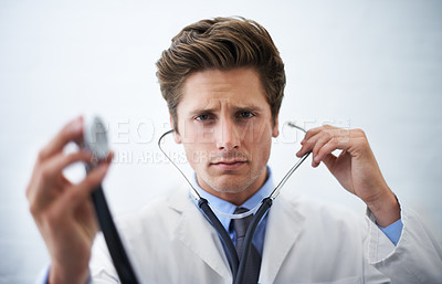 Buy stock photo Stethoscope, serious and portrait of doctor in office for medical consultation at hospital. Doubt, thinking and professional young male healthcare worker with equipment for career at medicare clinic