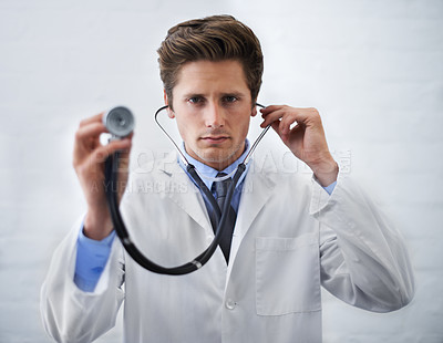 Buy stock photo Serious, portrait and man doctor with stethoscope in his office for medical consultation at hospital. Listen, career and professional young male healthcare worker or intern at medicare clinic.