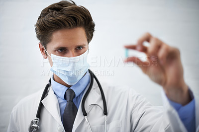 Buy stock photo Man, doctor and checking pill with face mask for healthcare, cure or drugs on a white studio background. Male person, surgeon or medical nurse looking at medication in research, study or examination