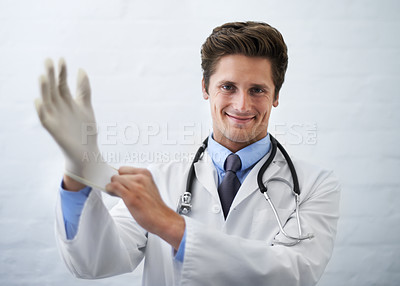 Buy stock photo Shot of a smiling doctor pulling on a surgical glove