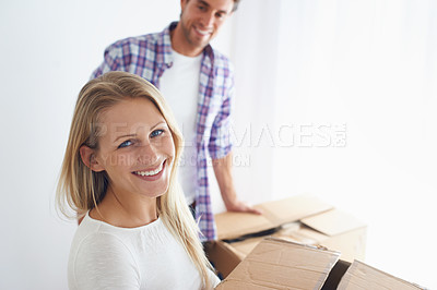 Buy stock photo A smiling woman carrying a brown cardboard box while her boyfriend looks on