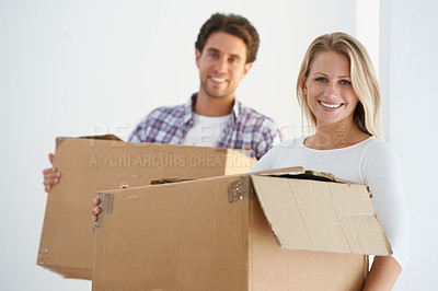 Buy stock photo Portrait of a happy couple carrying brown cardboard boxes in their new home