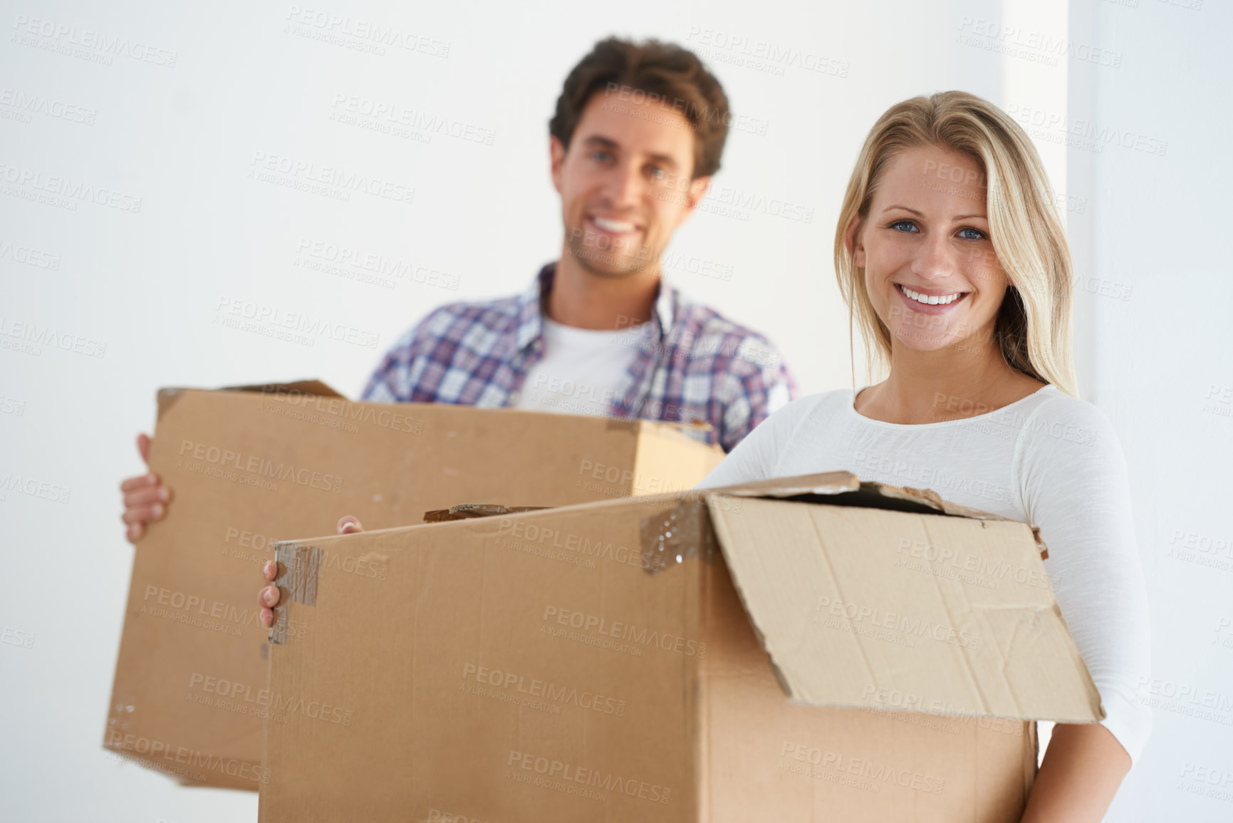 Buy stock photo Portrait of a happy couple carrying brown cardboard boxes in their new home