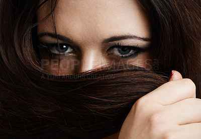 Buy stock photo Cropped portrait of a beautiful young woman covering her mouth with her hair
