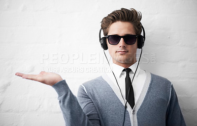 Buy stock photo A trendy young man holding out his palm while listening to music on his headphones