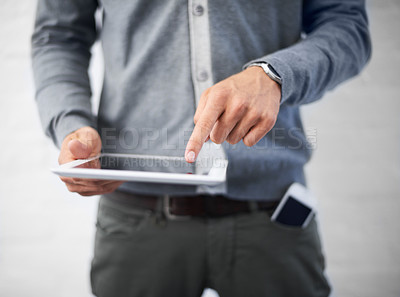 Buy stock photo Cropped image of a young man working on his digital tablet