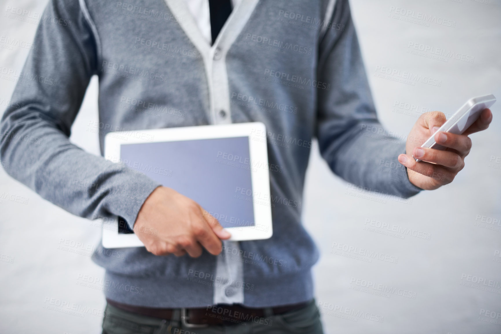 Buy stock photo Cropped image of a nerd holding a tablet pc while typing a message on his phone