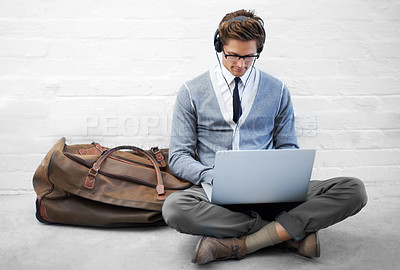 Buy stock photo Business man, reading or luggage with laptop, floor and music with app, flight or travel by wall background. Entrepreneur, person or employee with headphones, computer or audio streaming subscription