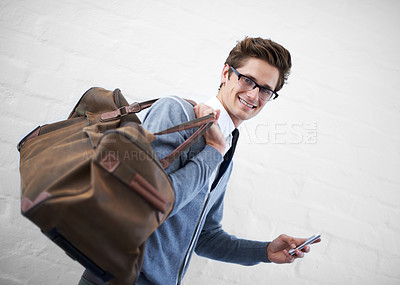 Buy stock photo Business man, bag and phone in portrait by wall background with click for booking app, schedule and travel. Entrepreneur, employee and smartphone for smile, reading and scroll on website for flight