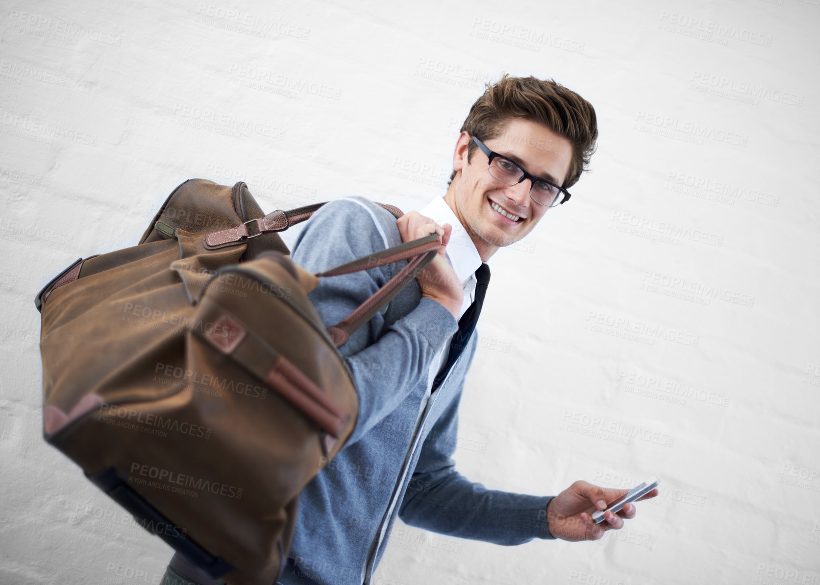Buy stock photo Business man, bag and phone in portrait by wall background with click for booking app, schedule and travel. Entrepreneur, employee and smartphone for smile, reading and scroll on website for flight